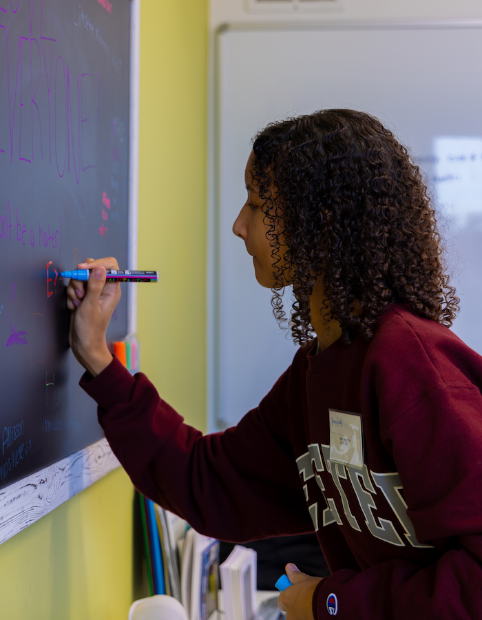 Beacon Academy student writing on black board